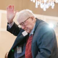 Don Lubbers, standing and being acknowledged by crowd, seen clapping in the background